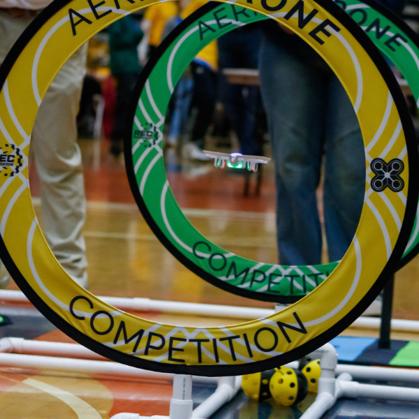 A small drone flies through circular hoops during a robotics competition