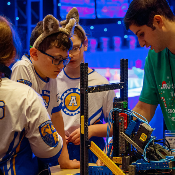 Elementary school robotics team collaborates around a VEX robot during tournament play