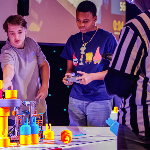 Middle school students operate a competition robot during a SCORE robotics match