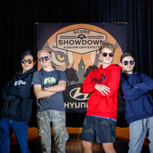 Students pose in front of a SCORE Showdown banner during a robotics tournament at Auburn University