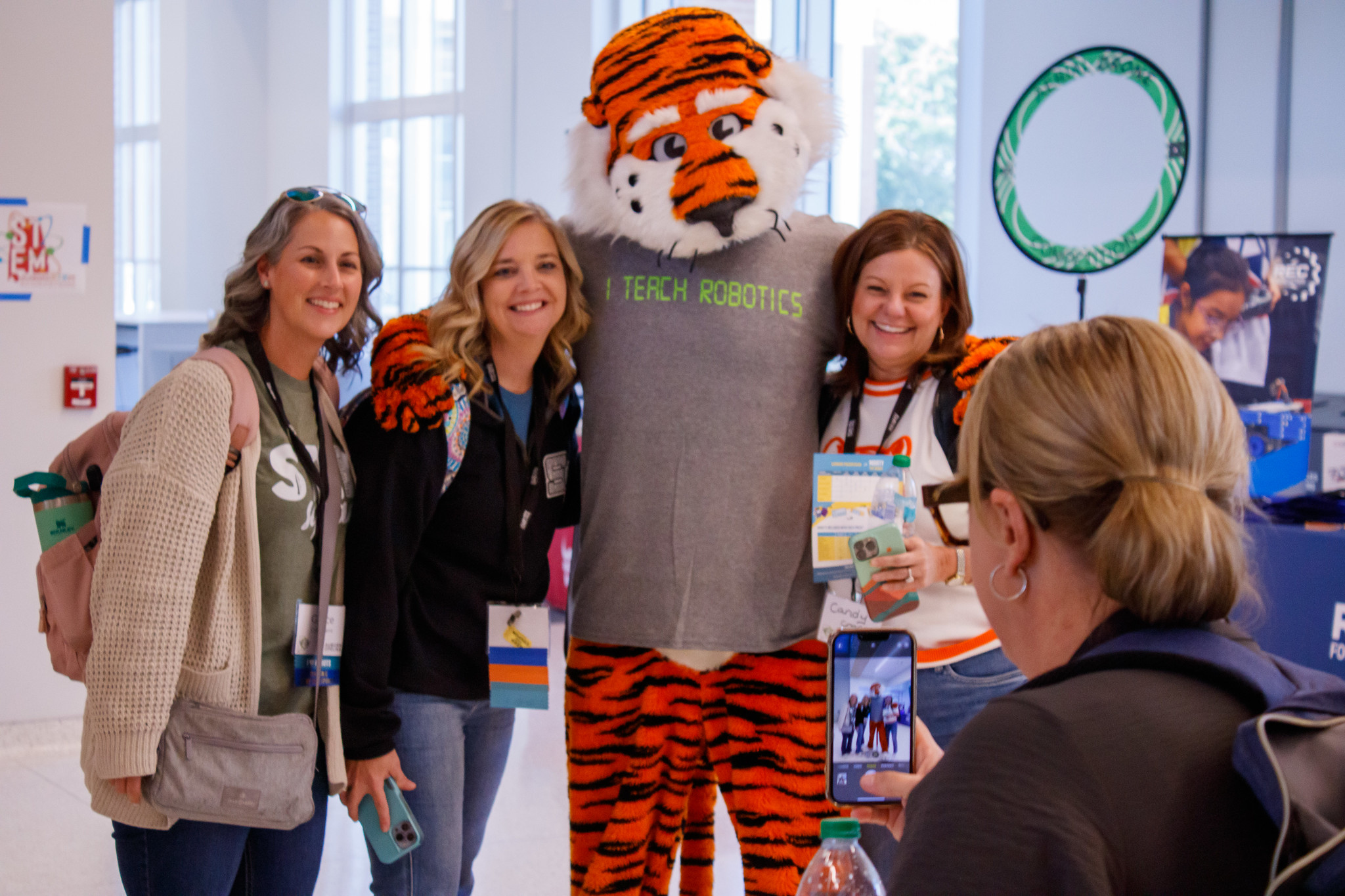a group of educators smiles for a photo with aubie the tiger